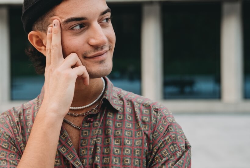 Junger Mann posiert mit Hand am Gesicht und Blick in die Kamera