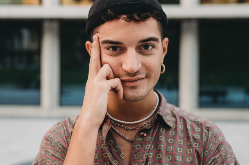 Junger Mann posiert mit Hand am Gesicht und Blick nach Links